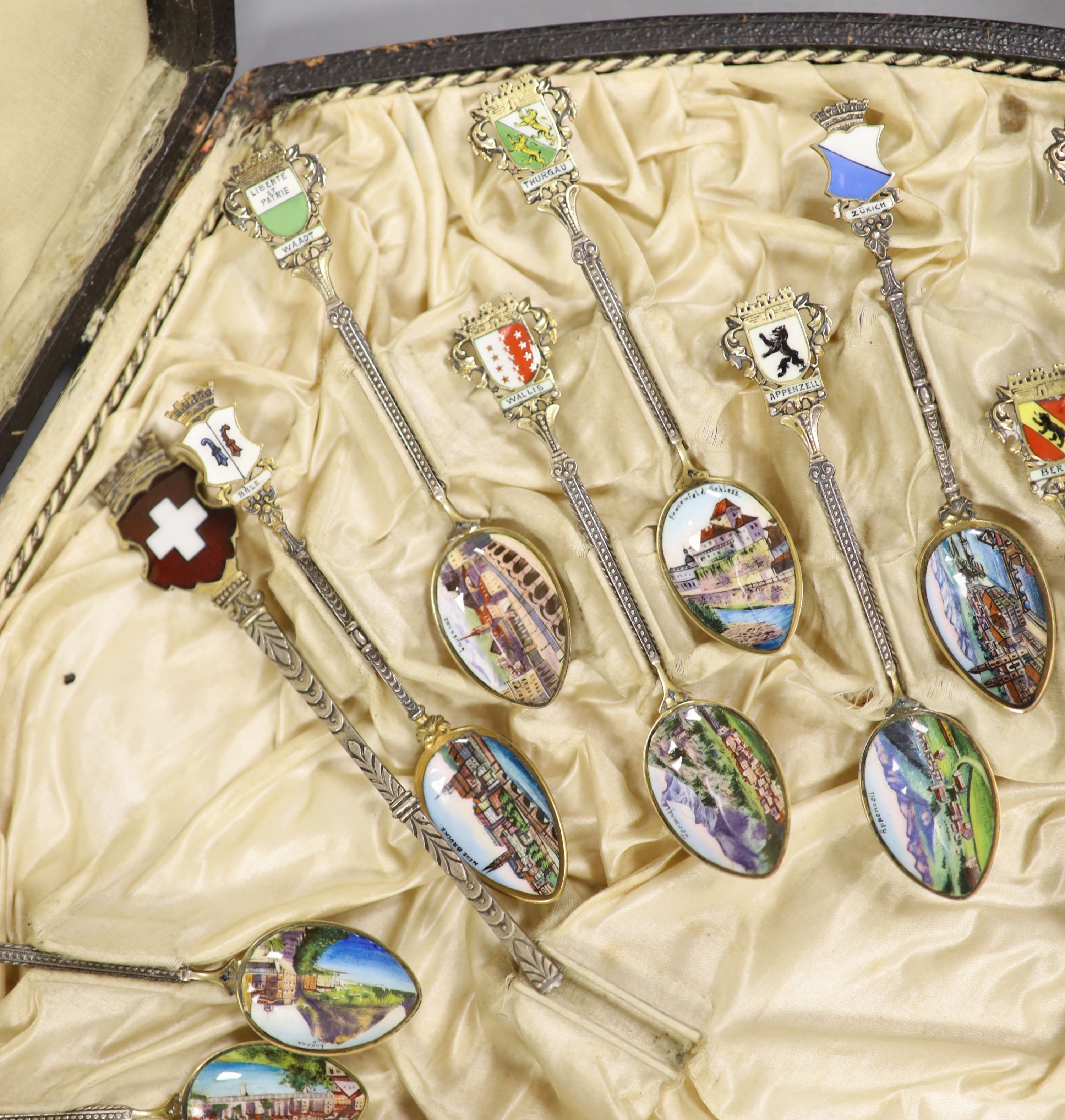 A set of 22 Swiss 800 silver and enamel souvenir spoons, each representative of a Canton, cased, with a larger spoon.